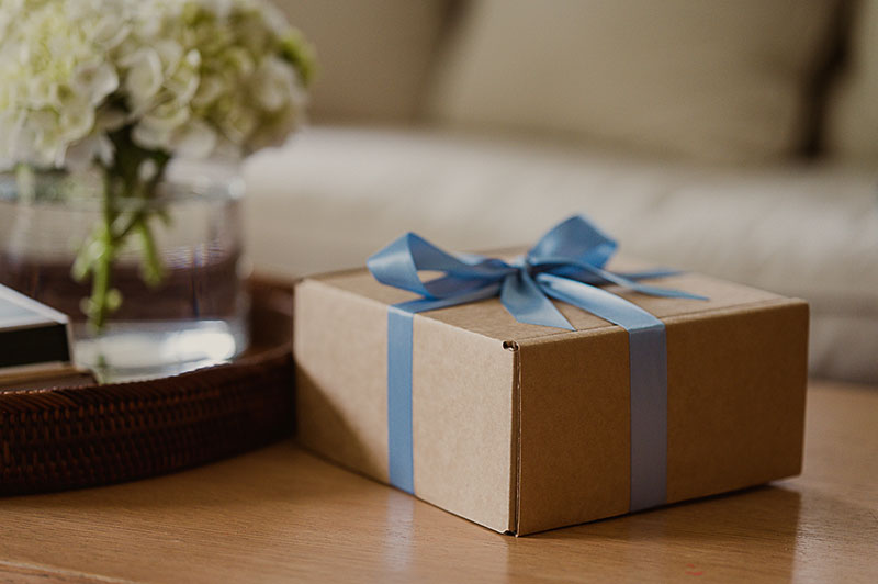 Gift box sitting on coffee table next to vase of flowers